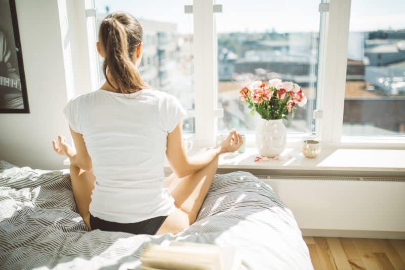 Beautiful woman practicing yoga in front of window of cozy apartment.Relaxation and mindfulness concept.