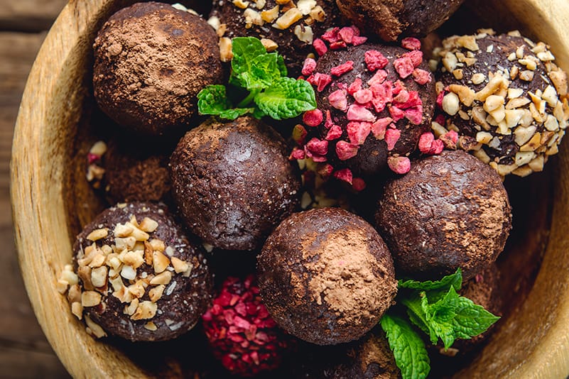 dark chocolare covered immunity boosting bliss balls in bowl with mint leaves