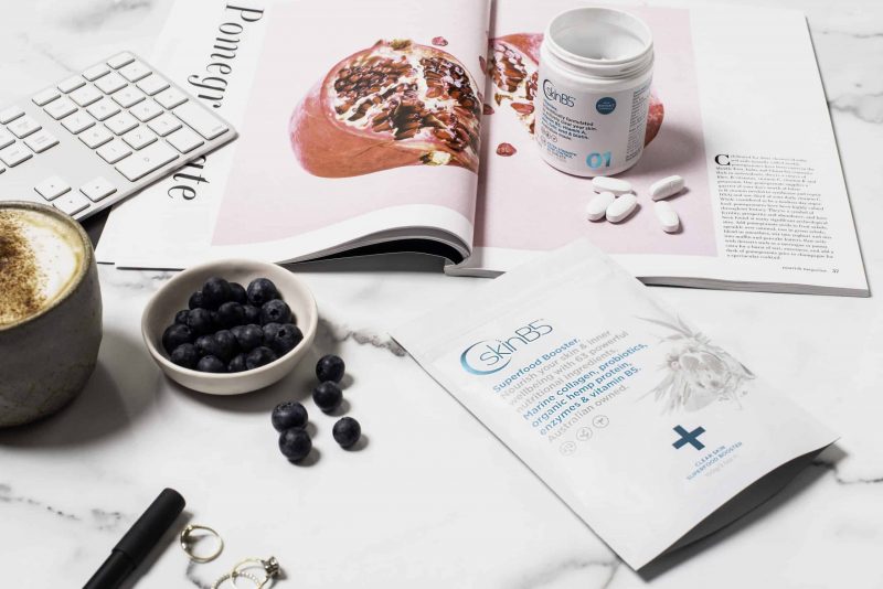 SkinB5 superfood and vitamins with magazine and blueberries on bench